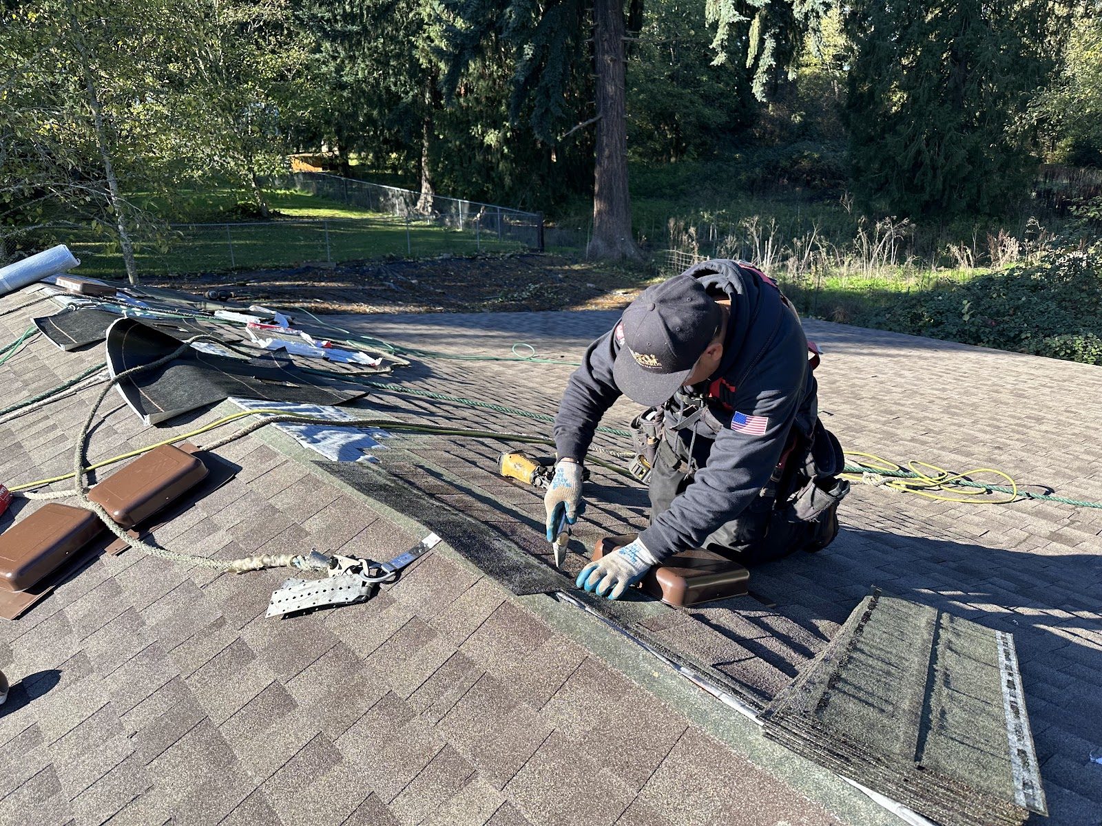 High Standards crew member hand-nailing shingles at the roof edge